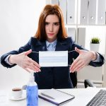 kobieta biznesu przy biurku z komputerem trzyma w dłoniach medyczną maskę