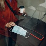Maska medyczna, dłonie, stół, laptop i telefon komórkowy