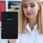 Uśmiechnięty portret bizneswoman trzyma kalkulator w ręku