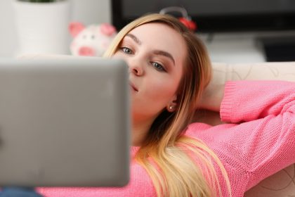 Młody piękny blondynki kobiety lying on the beach na kanapie ogląda pastylkę