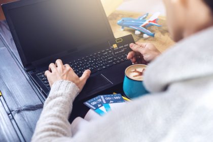 Mężczyzna trzyma kartę kredytową i kupuje bilety lotnicze w Internecie