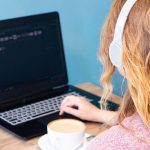 Dziewczyna z blondynem w hełmofonach pracuje dla laptopu