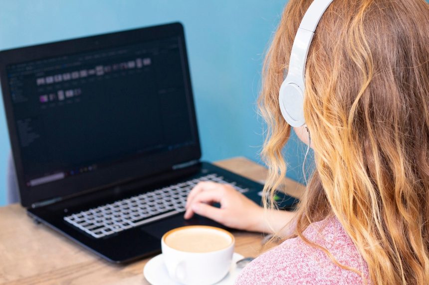Dziewczyna z blondynem w hełmofonach pracuje dla laptopu