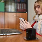 Młoda kobieta używająca laptopa siedząc na stole w domu