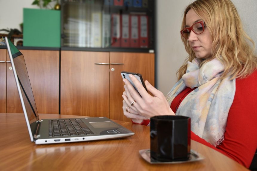 Młoda kobieta używająca laptopa siedząc na stole w domu
